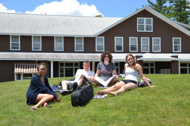 musicians sitting on a hill in front of the lodge at New England music camp